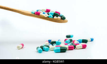 Colorful of antibiotics capsule pills in wooden spoon are spilling on white background with copy space. Antibiotic drug use with reasonable and health Stock Photo