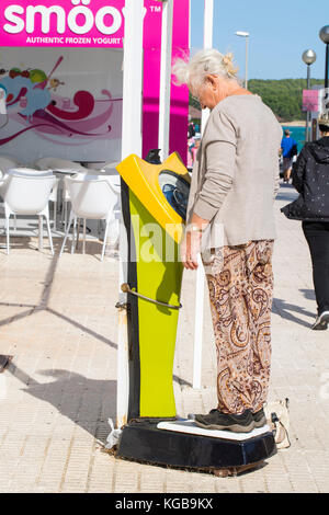 Elderly lady on holiday, weighing herself outside smoothie bar Stock Photo