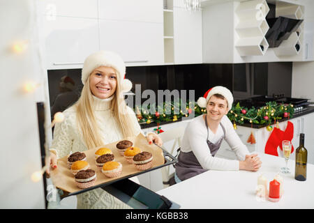 The family bakes cupcakes on Christmas in the kitchen.  Stock Photo