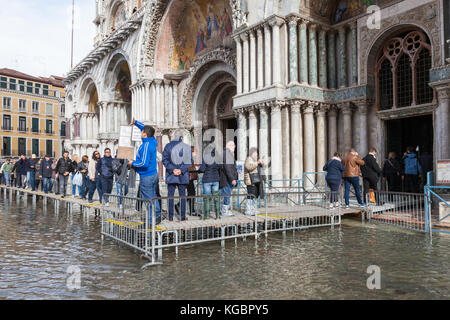 Venice, Veneto, Italy. 6th Nov, 2017. Acqua Alta high tide from the lagoon causing temporary flooding in Piazza San Marco. Passarelle, or elevated walkways, are installed for pedestrian traffic with tourists queuing to enter Basilica San Marco. Credit: Mary Clarke/Alamy Live News Stock Photo
