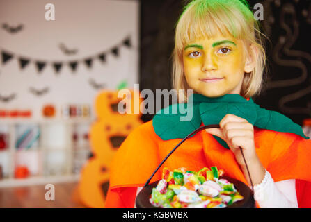Girl in pumpkin costume with a bowl of candies Stock Photo