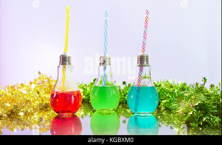Three colorful cocktails for party in light bulb shaped glasses. Copy space. Stock Photo