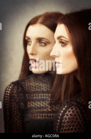 Woman with two faces in the mirror Stock Photo