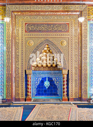 Golden ornate arched mihrab (niche) with floral pattern, blue Turkish ceramic tiles and arabic calligraphy at the public mosque of The Manial Palace o Stock Photo