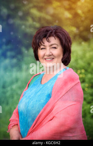 Portrait of the happy mature woman in the summer outdoors Stock Photo