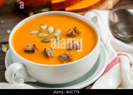 Pumpkin soup puree with seeds and wooden background. Stock Photo