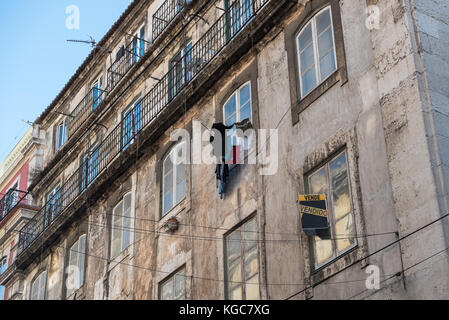 Street view of classic European apartment building with laundry hanging to dry outside and generic for sale sign on window Stock Photo