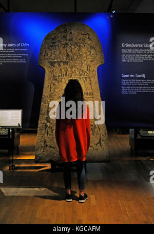 Historical Museum of Stockholm. Sweden. Girl contemplating the runic stone of Tangelgarda. 8th century. Iron age. From Larbro, Gotland island. Stock Photo