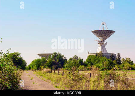 Large satellite dish radar antenna station in field against blue sky. Space Communication Center Stock Photo