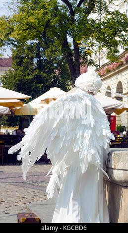 Girl in form of an angel in city. White live angel statue Stock Photo