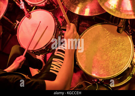 Drummer plays the drums at a concert in red light, the top view Stock Photo