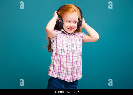Little girl in headphones with ponytails standing isolated on grey ...