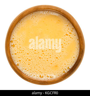 Raw scrambled eggs in wooden bowl. Yolk and white are stirred together and ready for further processing. Used for pancakes, omelettes or for breading. Stock Photo