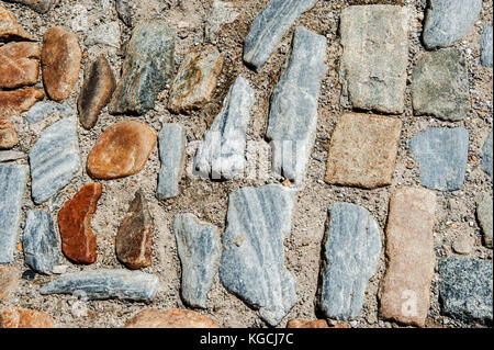 Beautiful multi-colored textured large stone cobbles in sand. The horizontal frame. Stock Photo