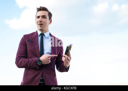 Young serious businessman in red suit and shirt with tie stand o Stock Photo