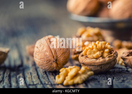 Walnut. Walnut kernels and whole walnuts on rustic old oak table. Stock Photo
