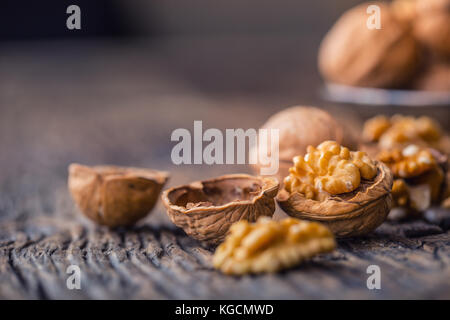Walnut. Walnut kernels and whole walnuts on rustic old oak table. Stock Photo