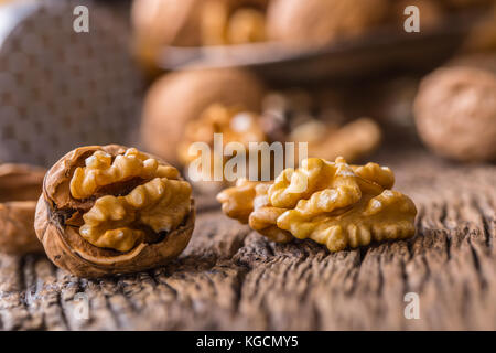 Walnut. Walnut kernels and whole walnuts on rustic old oak table. Stock Photo