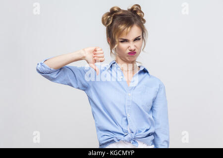 Young adult woman showing thumb down isolated on a gray background. Studio shot. Stock Photo