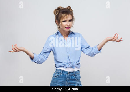 Negative human emotions. Upset young adult woman with hands out, shrugging her shoulders. Studio shot Stock Photo