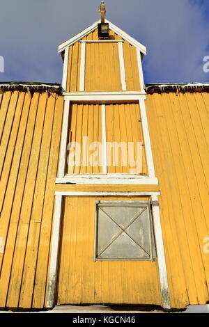 Old yellow port warehouse with closed doors-metal hatch in the lower one-old pulley on the upper one-crane location site closed-icicles hanging from r Stock Photo