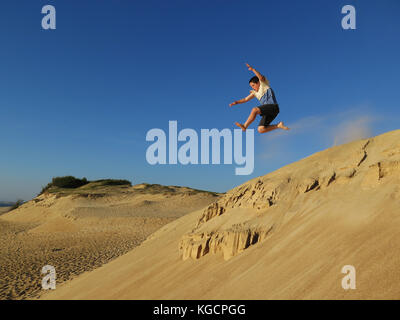 Young boy jumping of sand dunes in South-West France Stock Photo
