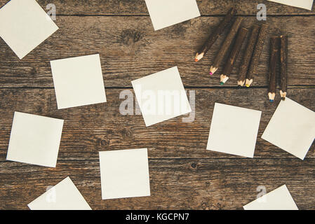 White paper stickers and colored pencils on wooden table Stock Photo