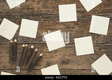 Sticky notes and colored pencils on vintage wooden background Stock Photo