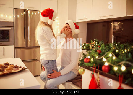 Couple hugging in the kitchen with lights for Christmas Stock Photo