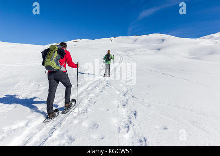Couple is snowshoe hiking in alpine winter mountains. Bavaria, Germany. Stock Photo