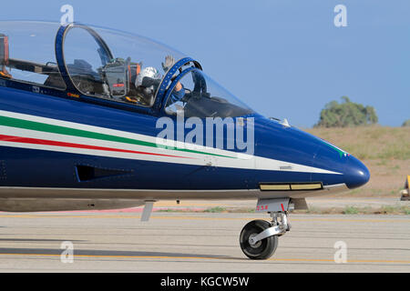A pilot in the cockpit of an Italian Air Force Frecce Tricolori aerobatic display aircraft waves to the crowd at an airshow Stock Photo