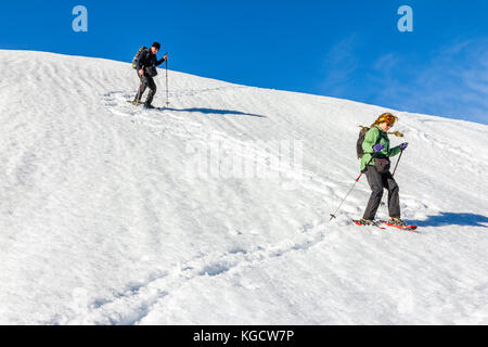 Senior couple is snowshoe hiking in alpine winter mountains. Bavaria, Germany. Stock Photo