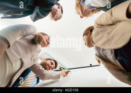 Low-angle view of the members of an international team working together for finding solutions during brainstorming session in the office Stock Photo