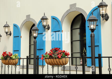 Exterior window decorated with shutters, lamps and flower vases Stock Photo