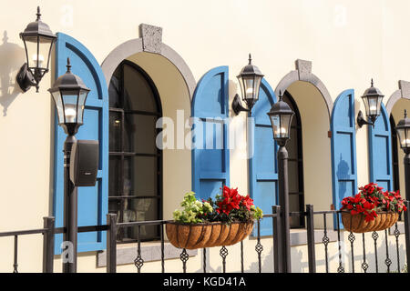 Exterior window decorated with shutters, lamps and flower vases Stock Photo