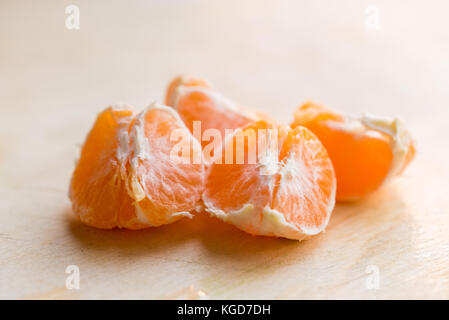 Studio shot of tangerine pieces without peel on white wooden board, healthy organic food concept Stock Photo