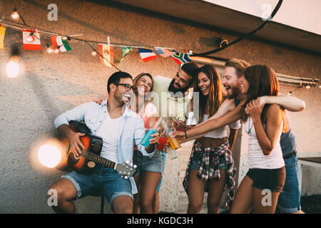 Group of happy friends having party on rooftop Stock Photo