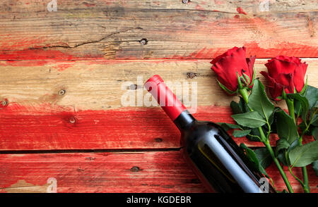 Valentines day concept. Red wine bottle and red roses on wooden background Stock Photo