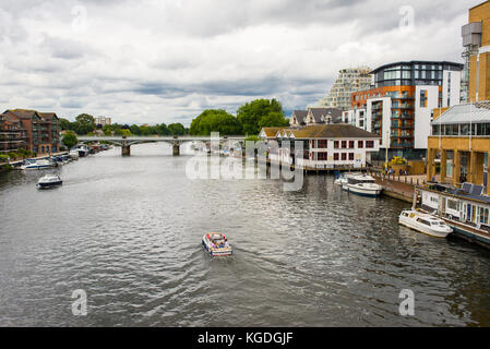 View of the river Thames with small boat passing and riverside apartments at Kingston-upon-Thames, a suburb of London, England, UK Stock Photo