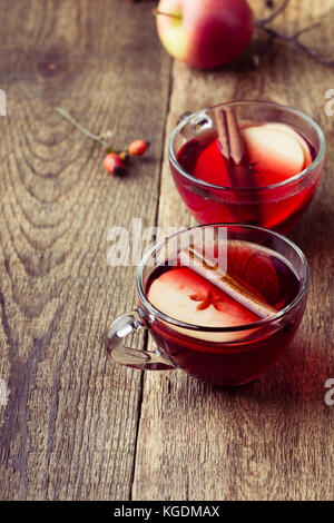 Mulled wine with apple slices in glass mugs on rustic wooden table served for two persons Stock Photo