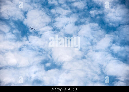 Passenger airline jet flying high overhead against a backdrop of white puffy clouds resembling cotton balls. (USA) Stock Photo