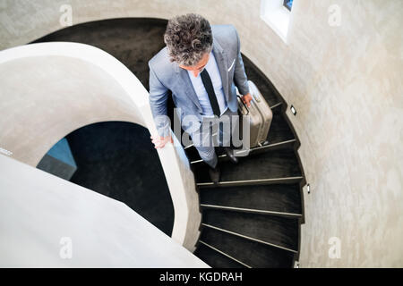 Businessman with suitcase walking down the stairs. Stock Photo