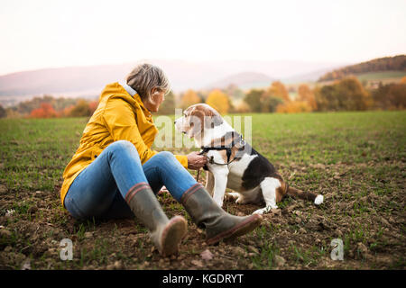 Senior woman with dog on a walk in an autumn nature. Stock Photo