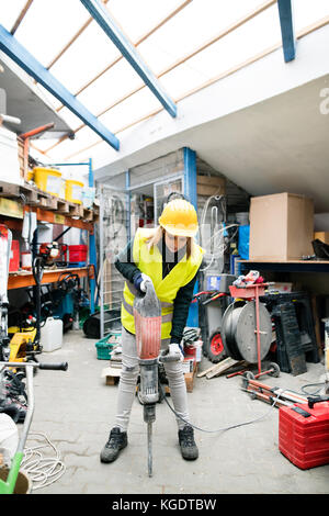 Female worker with jackhammer in a warehouse. Stock Photo