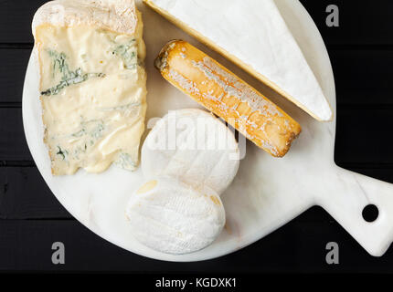 different kinds of italian cheese on a white marble cutting board . gorgonzola, goat, tomini and brie Stock Photo