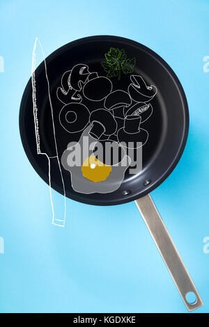 empty pan with non-stick coating and a steel pen isolated on blue and drawn egg fried eggs, mushrooms and knife chef Stock Photo