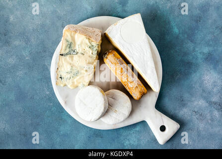 different kinds of italian cheese on a white marble cutting board . gorgonzola, goat, tomini and brie Stock Photo