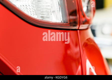 Car closeup with tail lights, indicators, blinkers and direction indicators. Red shiny paint of a brand new modern auto vehicle bumper. Stock Photo