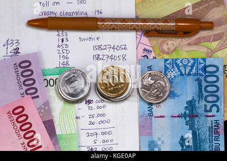 Top view/Flat Lay of Spending Money and Payment Illustrated with coins, bank notes, batik pen, and expense calculation in handwriting Stock Photo