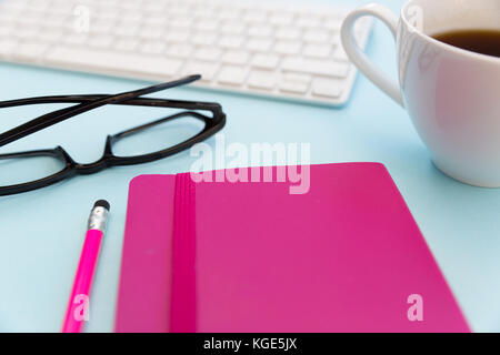 Computer keyboard pink notebook pencil coffee and eyeglesses closeup Stock Photo